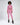 A model poses in a cropped pink sweatshirt and matching joggers, paired with black ankle boots.