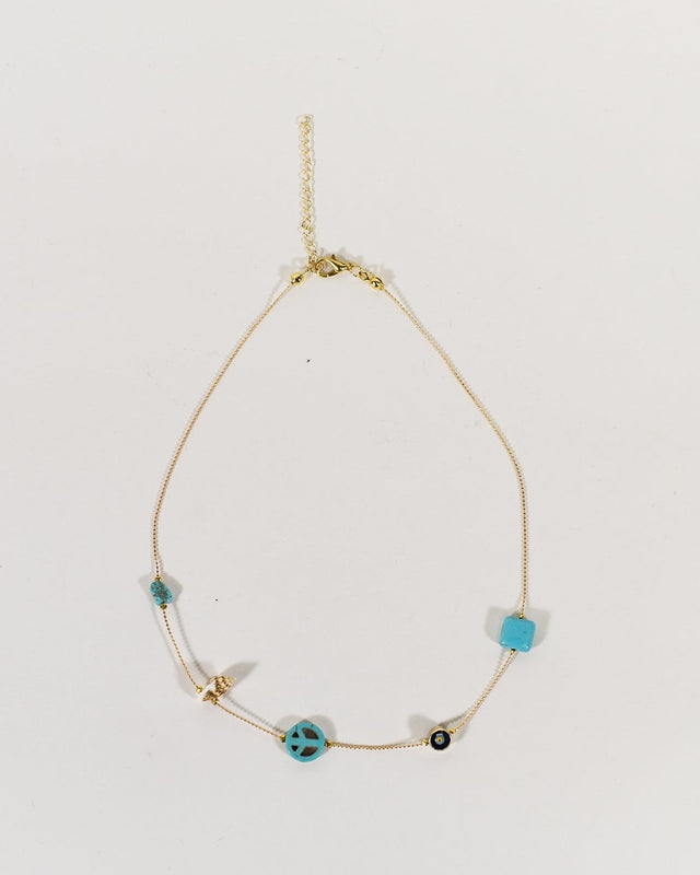 Dainty gold layering necklace featuring turquoise beads, evil eye, and peace sign charms with a lobster clasp closure.