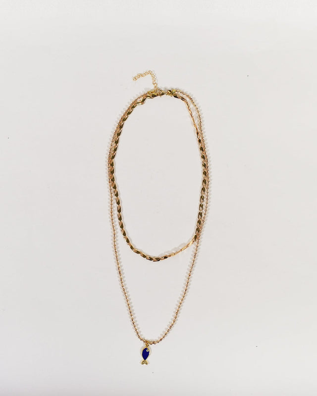 Layered golden necklace set featuring a textured choker and a long ball chain with a blue fish pendant.