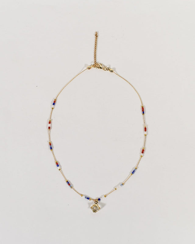 Golden initial E pendant necklace with red, white, and blue beads on a minimalist chain with a lobster clasp.