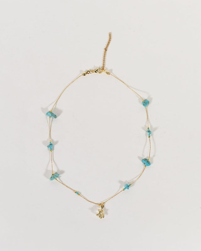 Dainty Golden Glow minimalist chain necklace with turquoise stone beads and a gold pendant on a white background.
