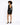 A model showcases a fitted black dress with long sleeves and an open back, paired with black high heels.