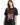 A woman in a black oversized tee featuring a graphic design with flames, a heart, and bold text.
