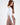 Back view of a white Adriana off-shoulder long sleeve crop top paired with brown high-waisted trousers.