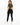 A woman in a cropped olive green top and black leggings poses from the back, showcasing a casual outfit.