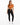 A woman stands confidently in a cropped, rust-colored top tied at the waist, paired with black leggings and white sne...