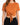 A woman is wearing a short-sleeve, rust-colored cropped top with a front knot, paired with black bottoms.