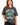 A woman wearing a loose-fitting gray t-shirt featuring a colorful graphic design with "New York" and decorative eleme...