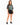 A woman stands wearing a loose-fitting graphic t-shirt with a New York design, paired with black shorts and sneakers.