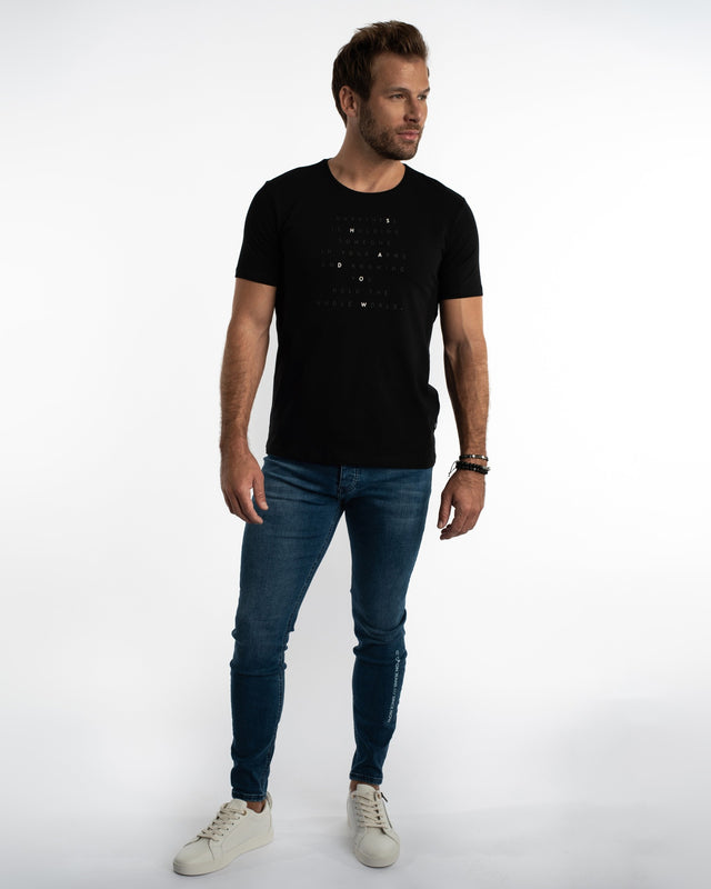 Man in Finn Blue Denim Jeans and black graphic t-shirt for a streetwear look against a white background.