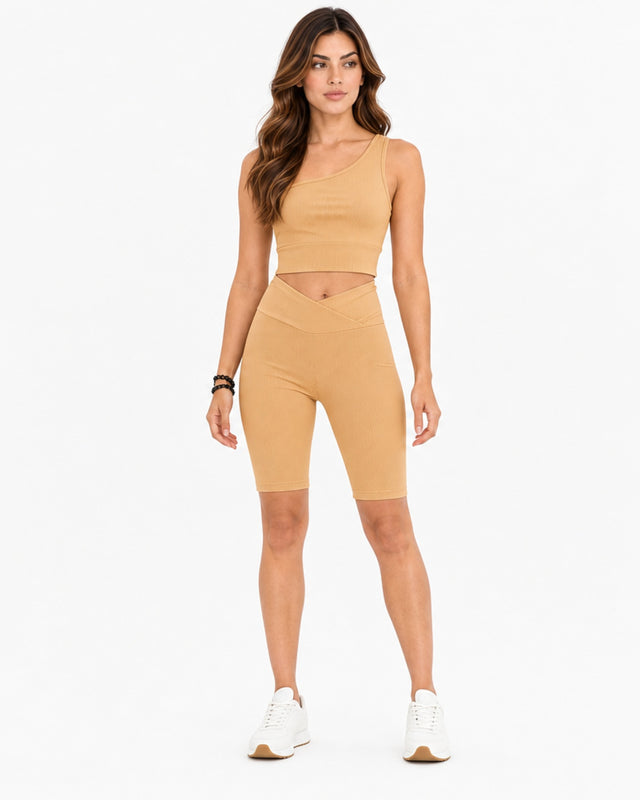 A model wearing a ribbed, beige crop top and matching high-waisted shorts, paired with white sneakers.