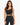 A woman with long, wavy hair wears a black ribbed crop top and matching high-waisted leggings.
