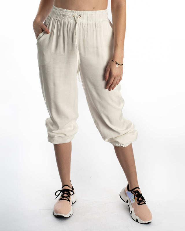 White Freya wide-leg pants featuring a high-waisted smocked drawstring and elastic cuffs on a model.