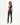 A woman in a fitted black crop top and sleek black pants poses from the back, showcasing a stylish look.