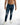 Men's Nixon blue distressed jeans with ripped knees and a faded wash, styled with white sneakers.