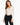 A model poses in a beige long-sleeve bodysuit with a deep V-neck and cut-out sides, paired with black jeans.