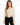A model wearing a fitted, ribbed long-sleeve bodysuit with cut-out sides, paired with black jeans.