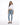 A woman stands confidently in a cropped white long-sleeve top, light blue jeans, and gray fuzzy slippers.