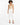 A model wearing a beige sleeveless bodysuit paired with white tailored pants and black strappy heels.