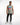 A man stands confidently in a sleeveless gray top with colorful text, paired with black jeans and white sneakers.