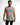 A man wearing a sleeveless light gray top with colorful "GAME OVER" graphic text and black jeans.