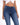 A close-up of a person wearing a white cropped top and dark blue fitted jeans, showcasing a casual style.