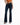 A person wearing a tied orange top and dark flared jeans, standing in black heeled sandals against a white background.