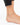 Ankle with a delicate gold chain featuring blue eye-shaped beads, resting on a bare foot.
