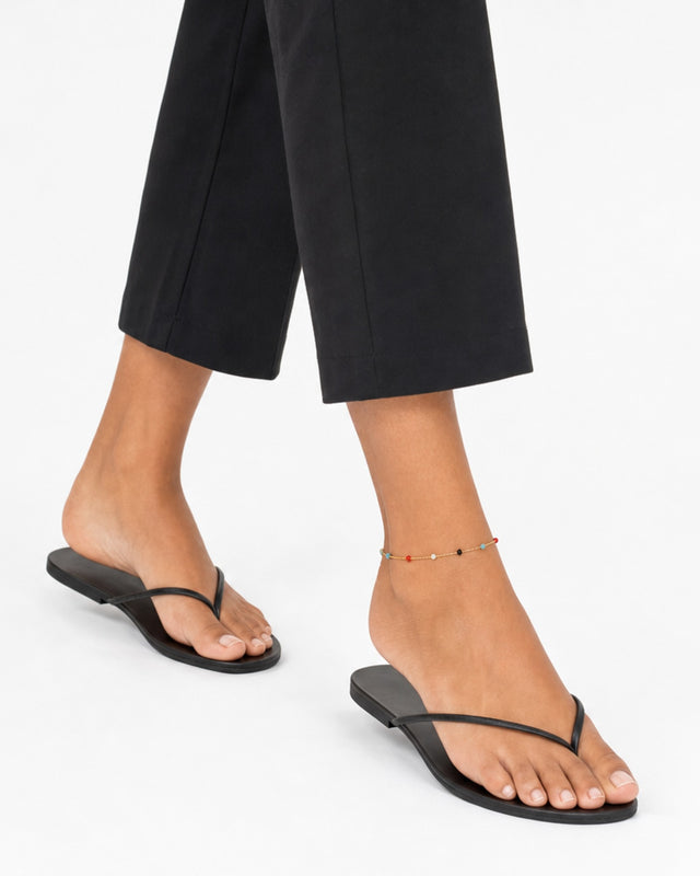 Ankle with a colorful beaded chain, paired with black flip-flops and cropped black pants.