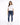 A woman stands confidently in a white t-shirt and distressed blue jeans, paired with white sneakers.
