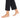 A bare foot with a delicate gold anklet featuring colorful charms, paired with black cropped pants.