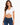 A woman models a white cropped top with a ruched front, paired with dark blue jeans.