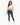 A woman stands confidently in a cropped white top and fitted blue jeans, paired with white sneakers.