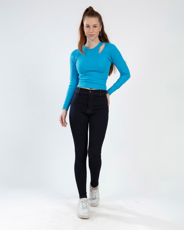 Model wearing the Goldie long sleeve blue ribbed crop top with a shoulder cutout and high-waisted dark jeans.