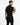 A man in a black overall stands with his back to the camera, showcasing a relaxed fit and short sleeves.