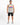 A man stands confidently wearing a sleeveless gray top with colorful graffiti-style text, paired with distressed blac...