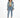 A woman stands confidently in a cropped denim jacket, fitted top, and high-waisted jeans, paired with white sneakers.