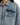 Close-up of a denim jacket featuring a zippered front and a chest pocket, showcasing a light blue wash and textured f...