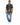 A man stands wearing a short-sleeve black shirt with a cream abstract pattern, paired with light blue jeans and white...