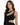 A model showcases a sleek black dress with a unique cutout design and asymmetrical neckline.