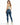 A woman with long hair wears a light green crop top and fitted blue jeans, paired with white sneakers.