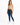 A woman stands confidently in a light green cropped top and dark blue skinny jeans, paired with white sneakers.