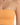 Close-up of a cropped top in a soft orange hue, featuring thin spaghetti straps and a ribbed texture.