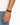 A close-up of a hand wearing a double-stranded brown bracelet with a black clasp.