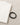 A folded light-colored shirt next to a black elastic bracelet on a textured beige surface.