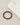 A circular bracelet featuring black beads interspersed with metallic gold accents, placed beside a folded light-color...