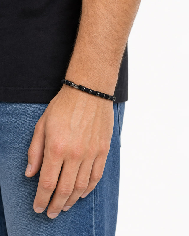 A close-up of a hand wearing a black beaded bracelet, showcasing a simple and modern design.