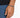 A close-up of a hand wearing a beaded bracelet with a mix of gray and black stones, resting on denim.