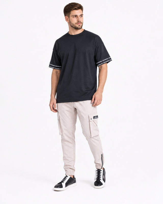 Light beige cargo pants with side pockets, paired with a black t-shirt and stylish black sneakers.