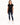 A woman stands wearing a black short-sleeve top with a heart design, paired with distressed blue jeans and white snea...
